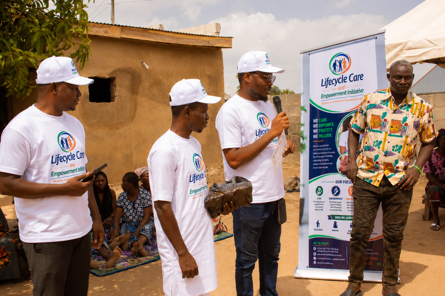 Lifecycle Care team addressing community members beside the official banner